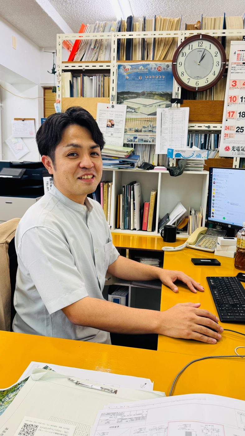 事務所のデスクで笑顔を見せる代表の吉田康平