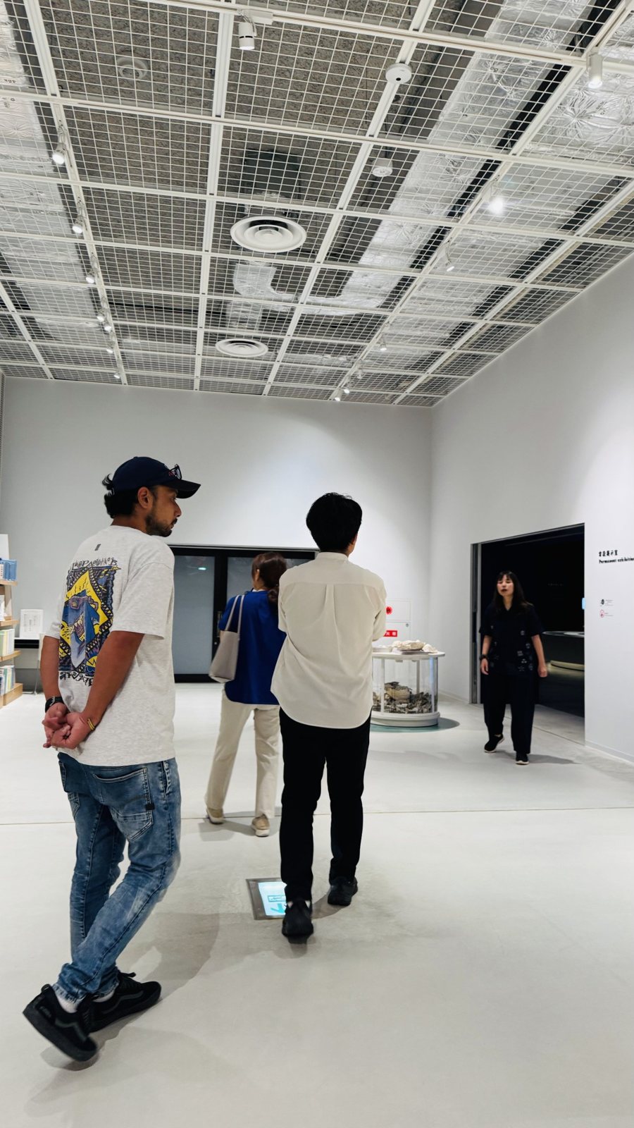 展示施設の天井や照明を見ながら歩く社員